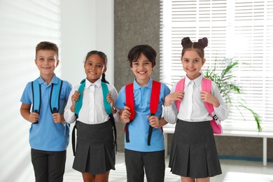 Happy children in school uniform with backpacks indoors