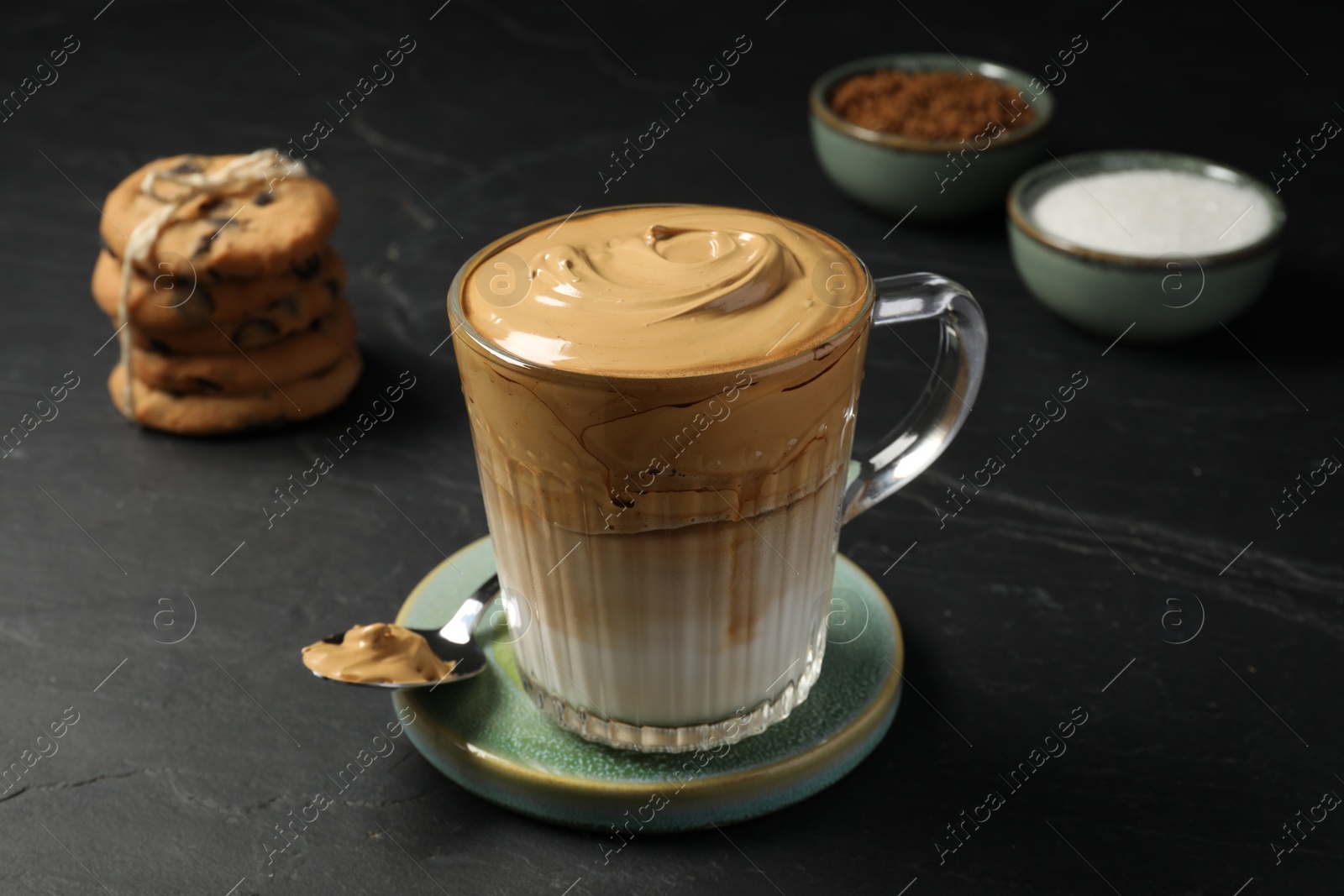 Photo of Glass mug of delicious dalgona coffee on dark table