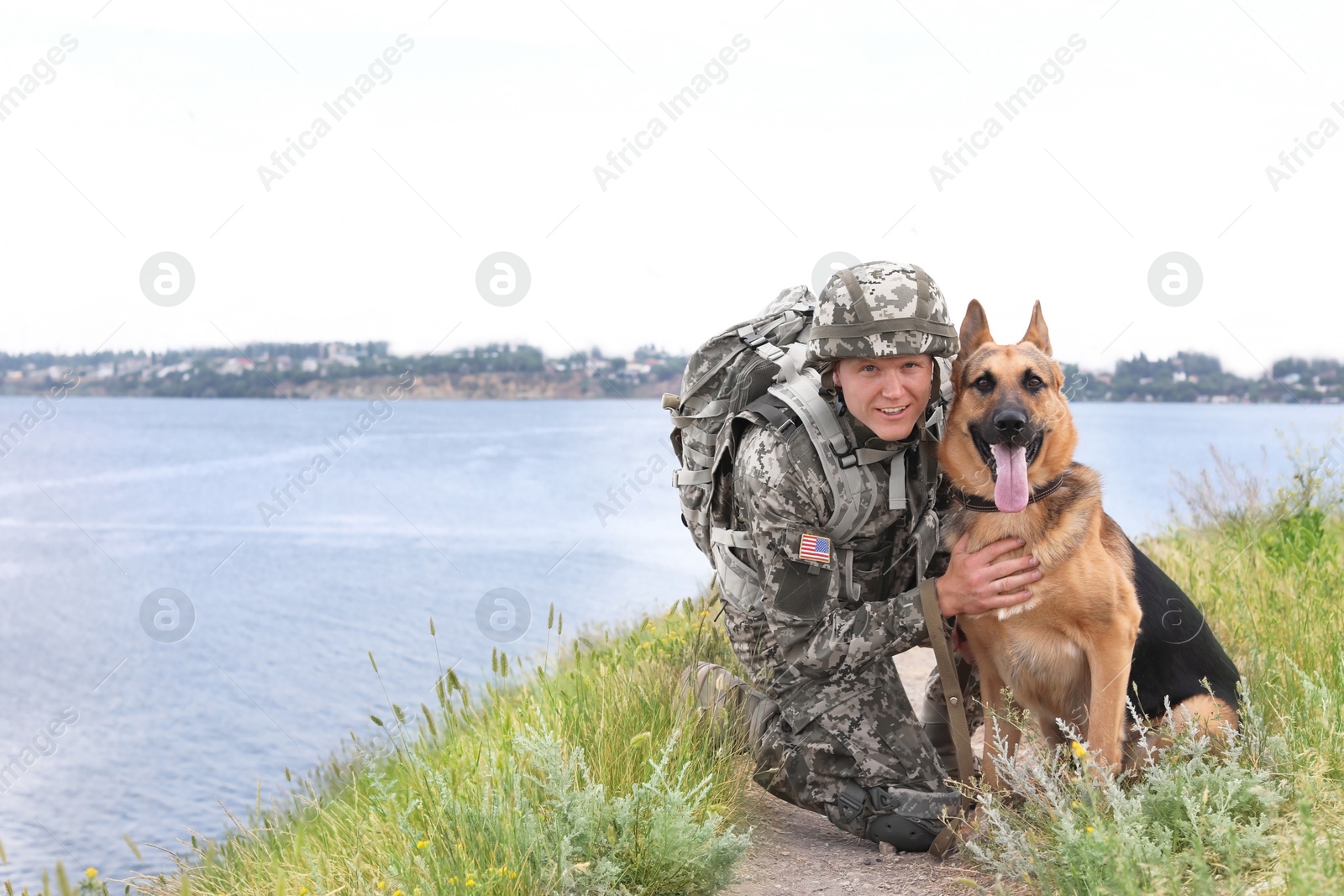 Photo of Man in military uniform with German shepherd dog near river