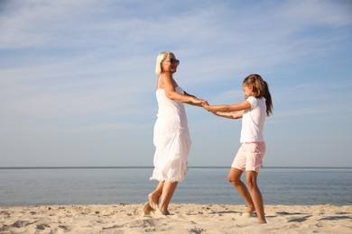 Cute little girl with grandmother spending time together on sea beach