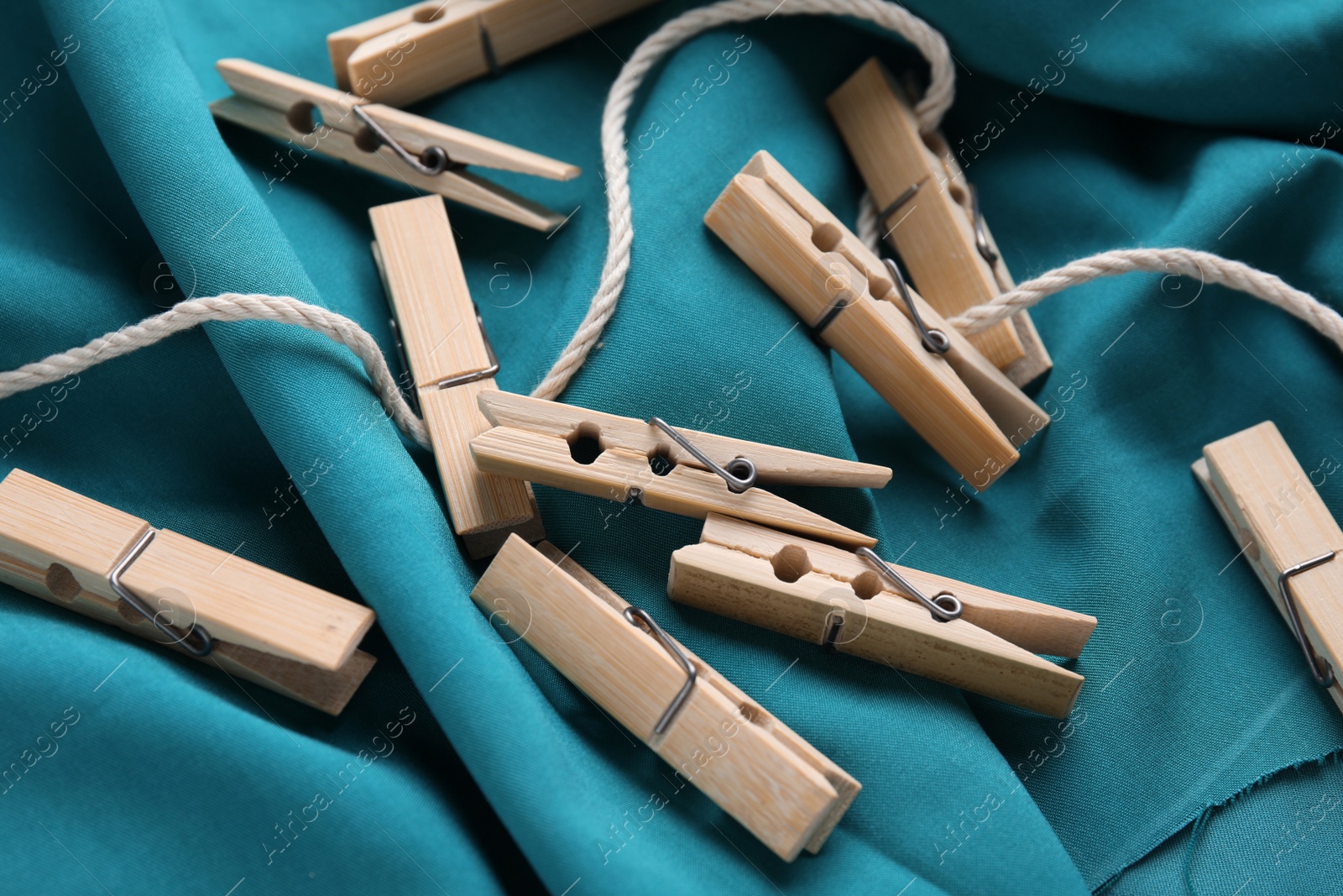 Photo of Many wooden clothespins and twine on teal fabric