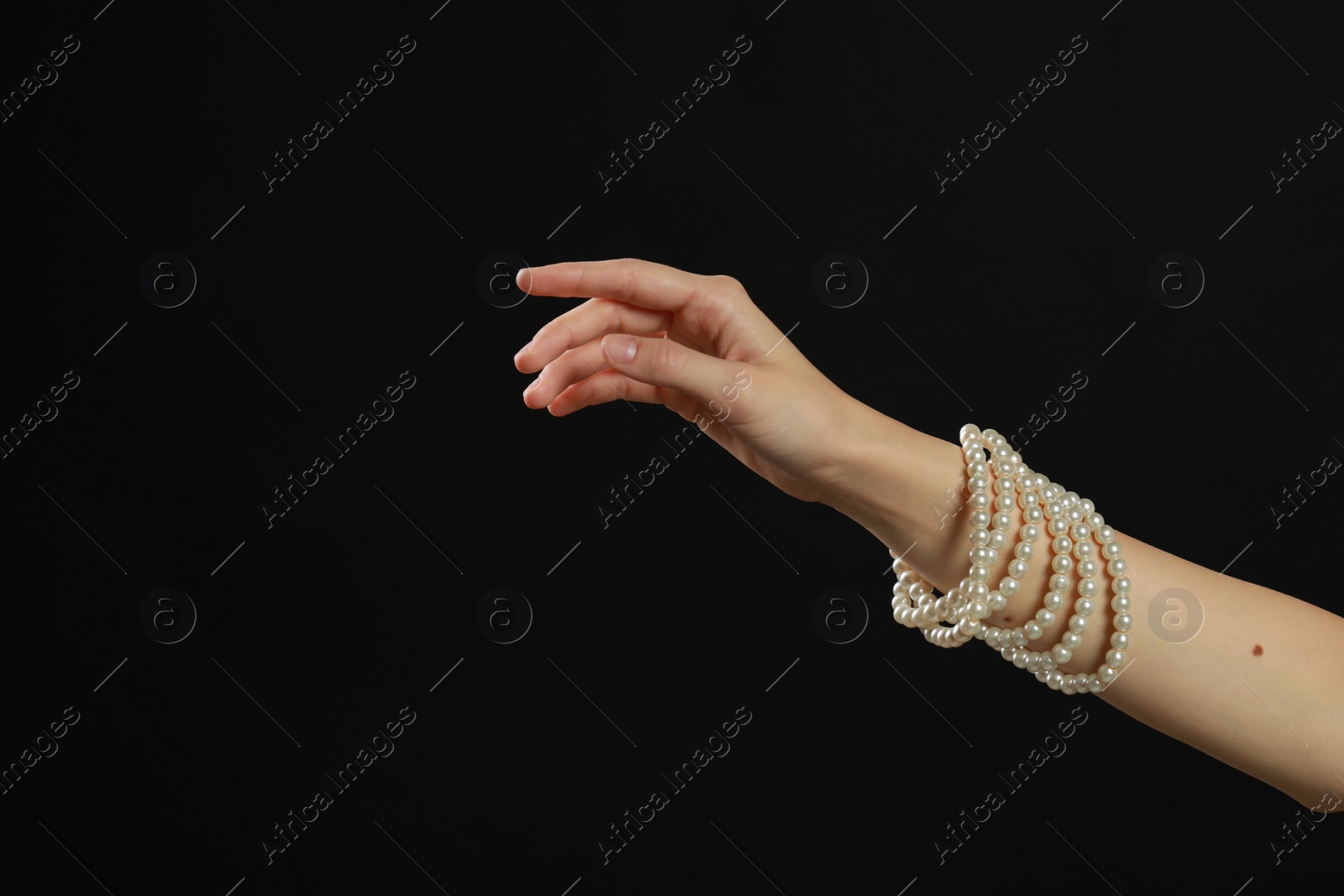 Photo of Young woman with elegant pearl jewelry on black background, closeup. Space for text