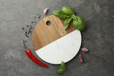 Photo of Cutting board, basil, pepper, chili peppers and garlic on grey table, flat lay. Space for text