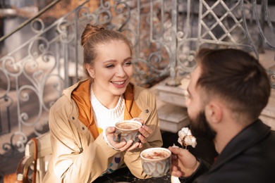 Photo of Lovely young couple enjoying tasty coffee at table outdoors