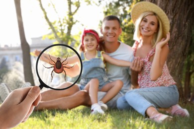 Image of Family sitting near tree outdoors and don't even suspect about hidden danger in green grass. Woman showing tick with magnifying glass, selective focus