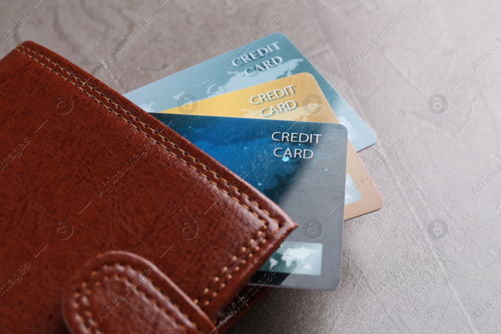 Photo of Credit cards and leather wallet on grey textured table, closeup