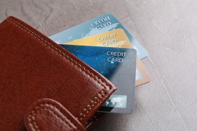 Credit cards and leather wallet on grey textured table, closeup