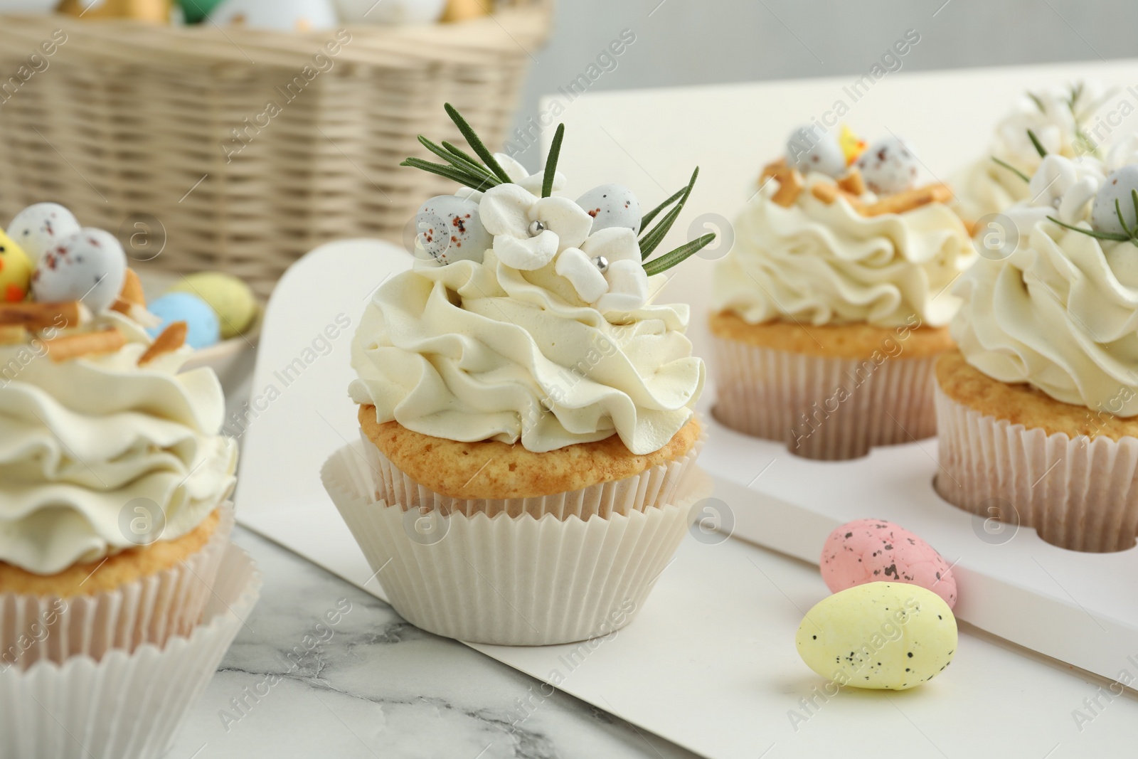 Photo of Tasty Easter cupcakes with vanilla cream on white marble table