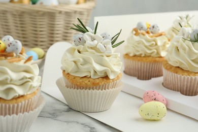 Photo of Tasty Easter cupcakes with vanilla cream on white marble table