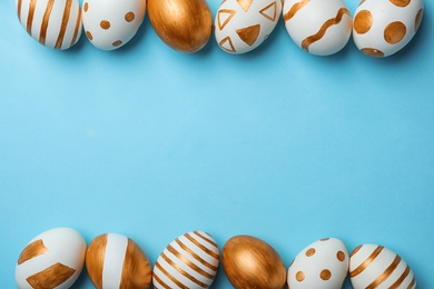 Set of traditional Easter eggs decorated with golden paint on color background, top view. Space for text