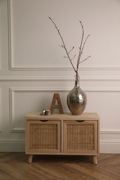 Photo of Tree twigs and decor on wooden table near white wall in room