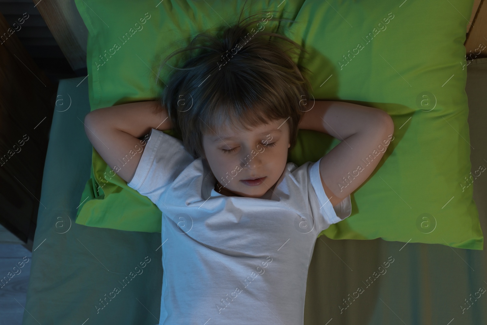 Photo of Little boy snoring while sleeping in bed at night, top view