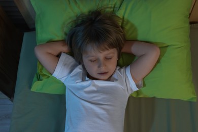 Photo of Little boy snoring while sleeping in bed at night, top view