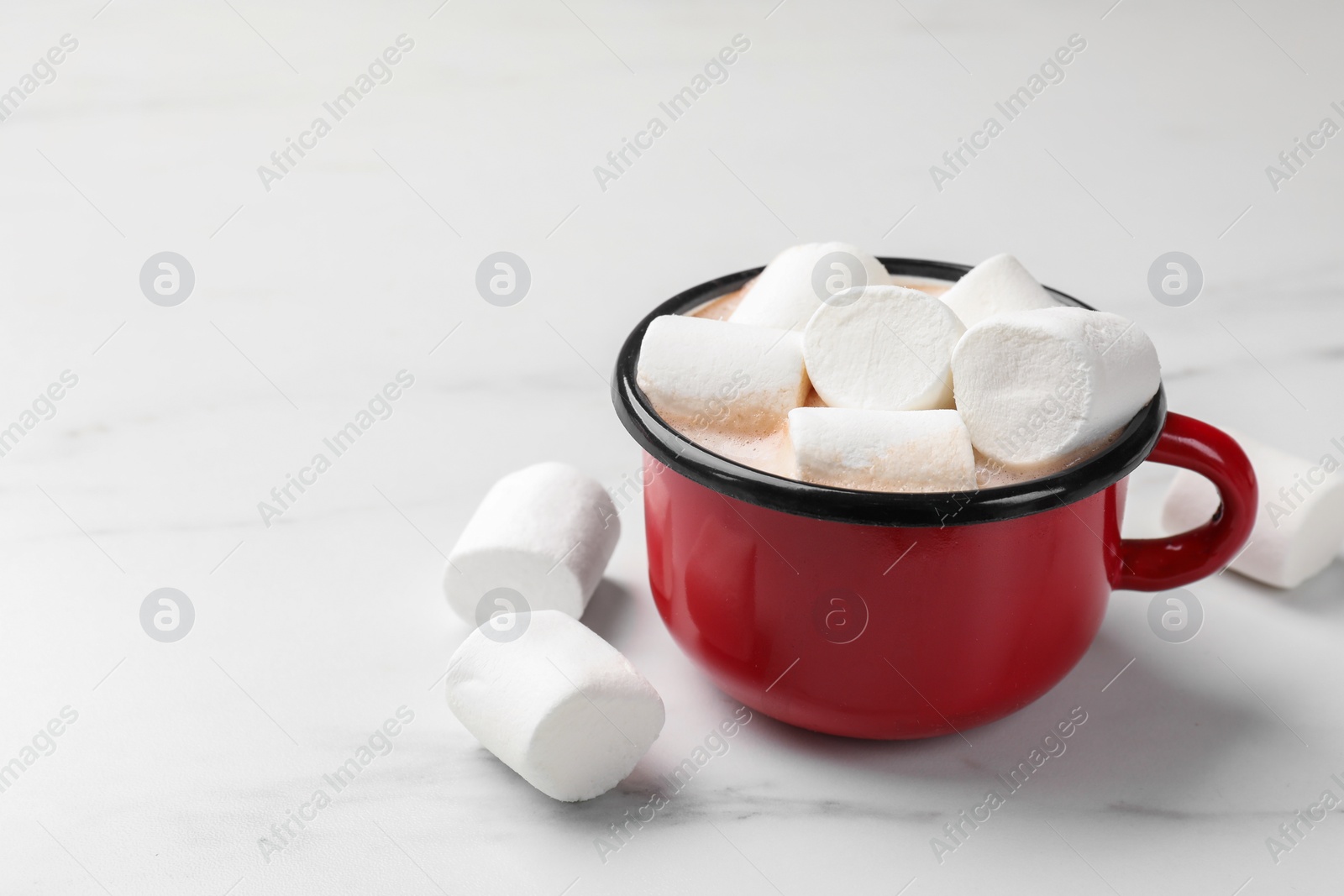 Photo of Tasty hot chocolate with marshmallows on white marble table, closeup. Space for text