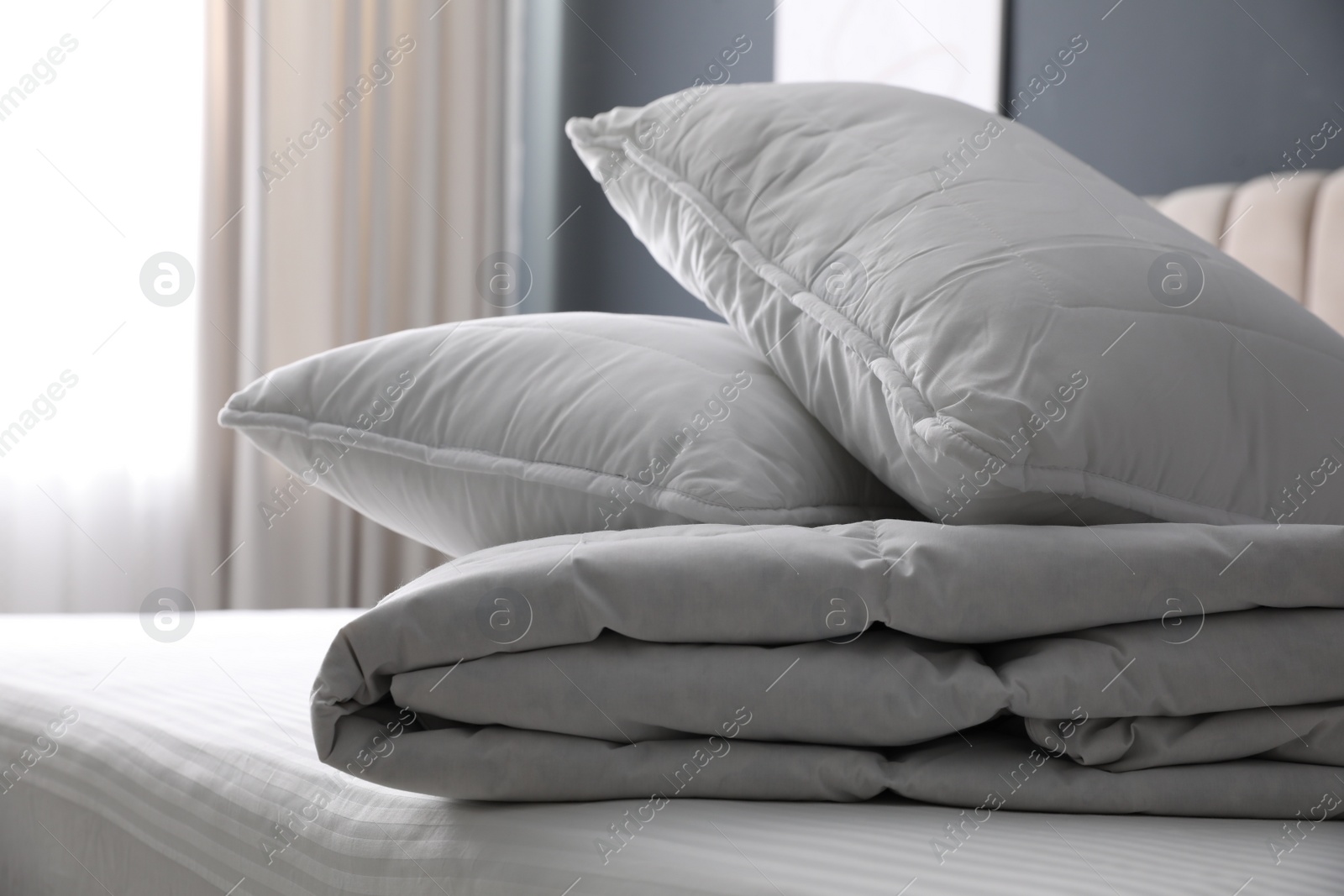 Photo of Soft folded blanket and pillows on bed indoors, closeup