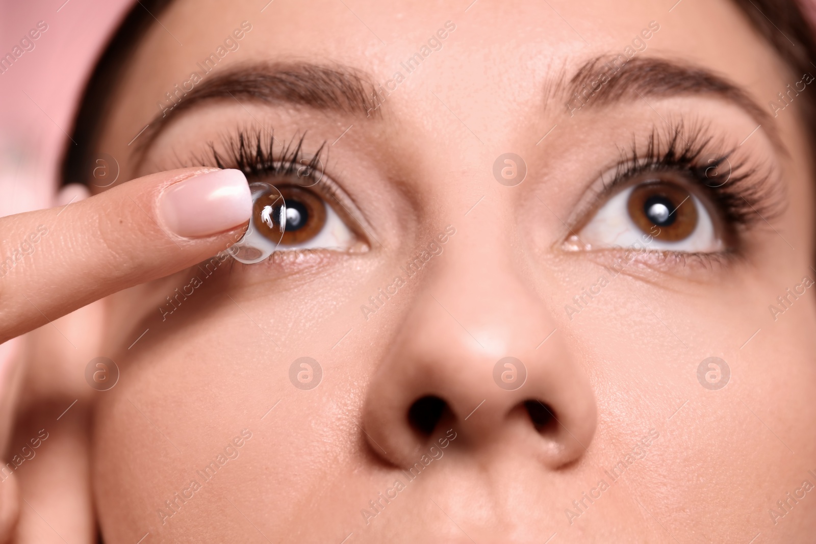 Photo of Young woman putting contact lens in her eye, closeup