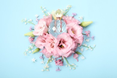 Luxury perfume and floral decor on light blue background, flat lay