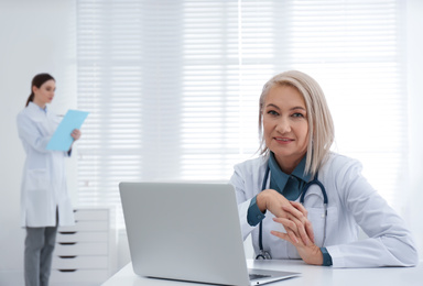 Portrait of mature female doctor in white coat at workplace