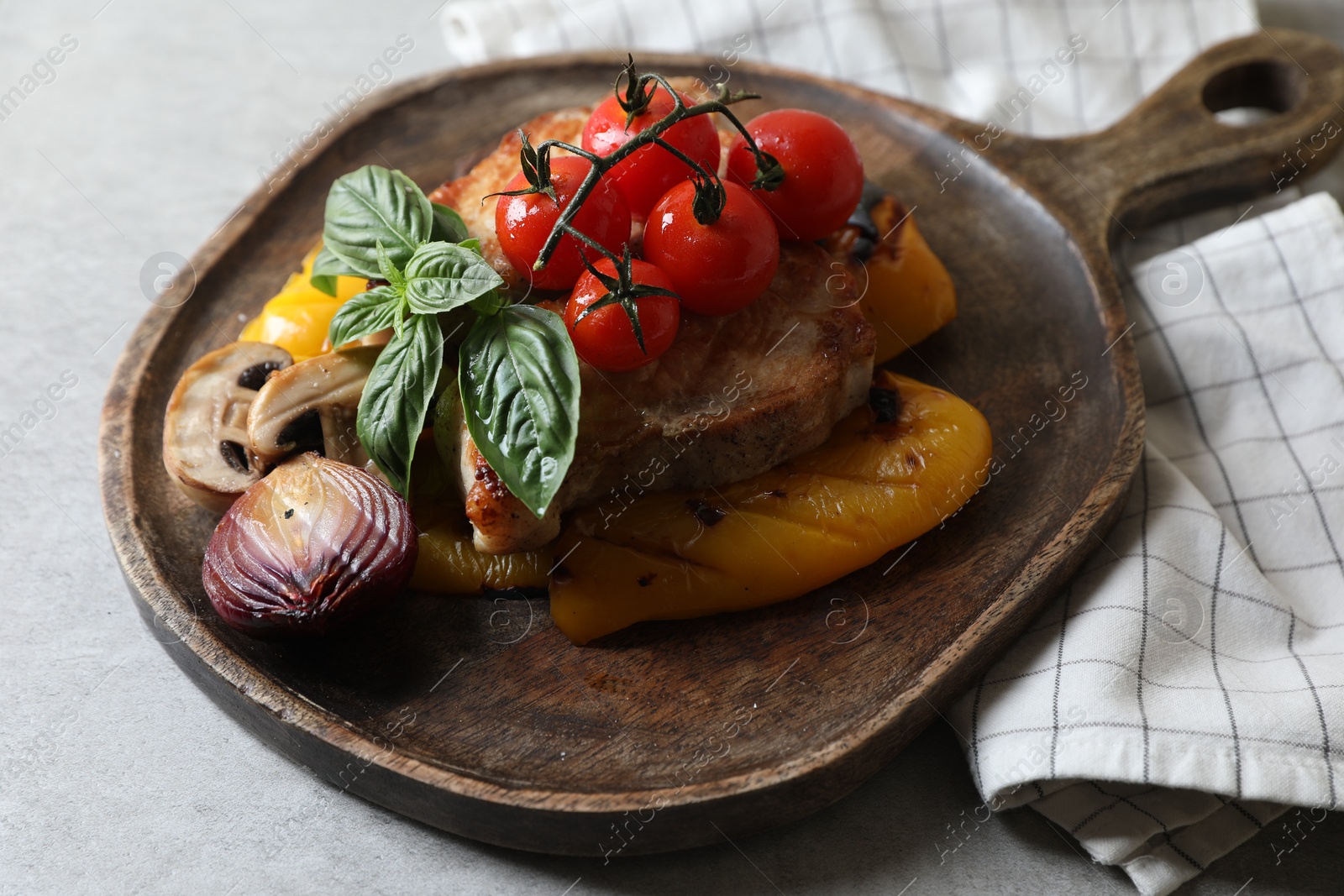 Photo of Serving board with tasty grilled meat and vegetables on light table, closeup