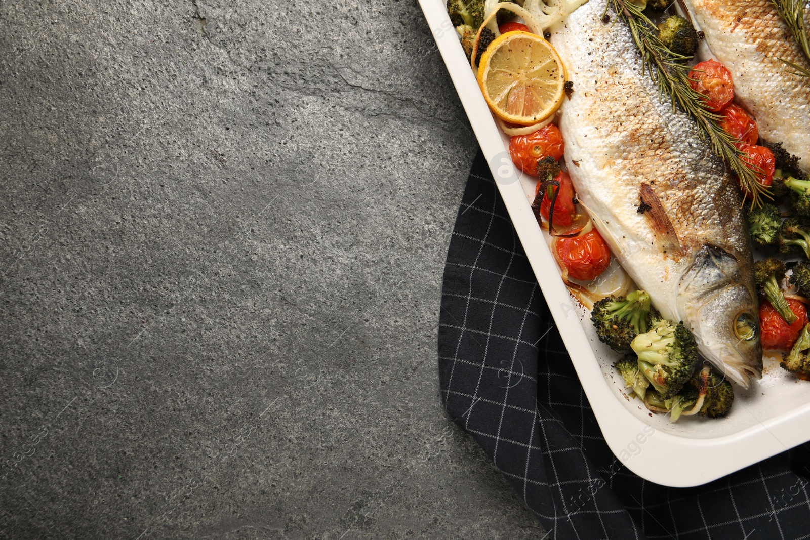 Photo of Delicious fish with vegetables and lemon in baking dish on grey textured table, top view. Space for text