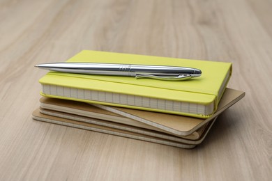 Photo of Stack of planners and pen on wooden table