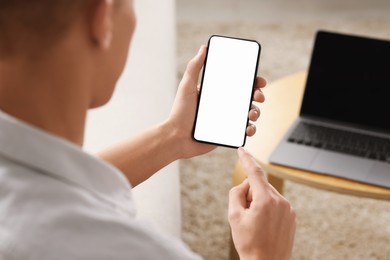 Man using smartphone with blank screen indoors, closeup. Mockup for design