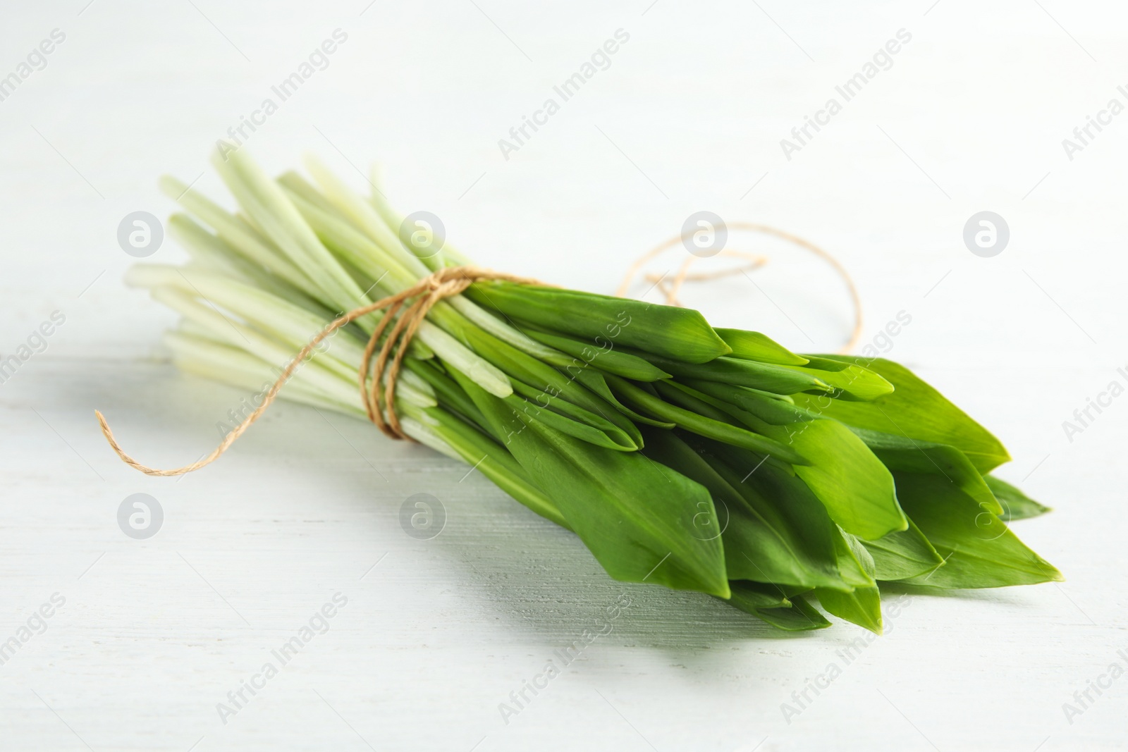 Photo of Bunch of wild garlic or ramson on white wooden table, closeup