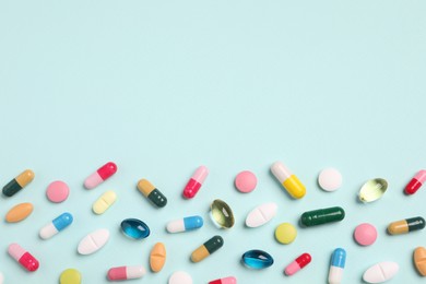 Photo of Many different pills on light turquoise background, flat lay. Space for text