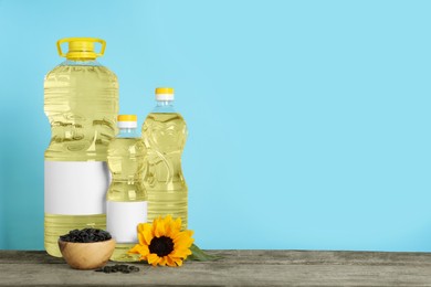 Bottles of cooking oil, sunflower and seeds on wooden table, space for text