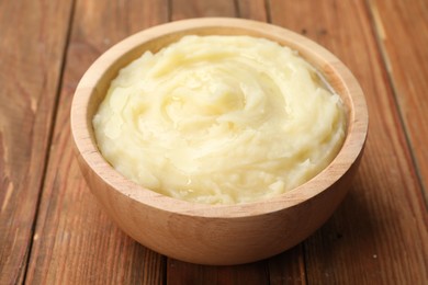 Photo of Bowl of tasty mashed potato on wooden table, closeup