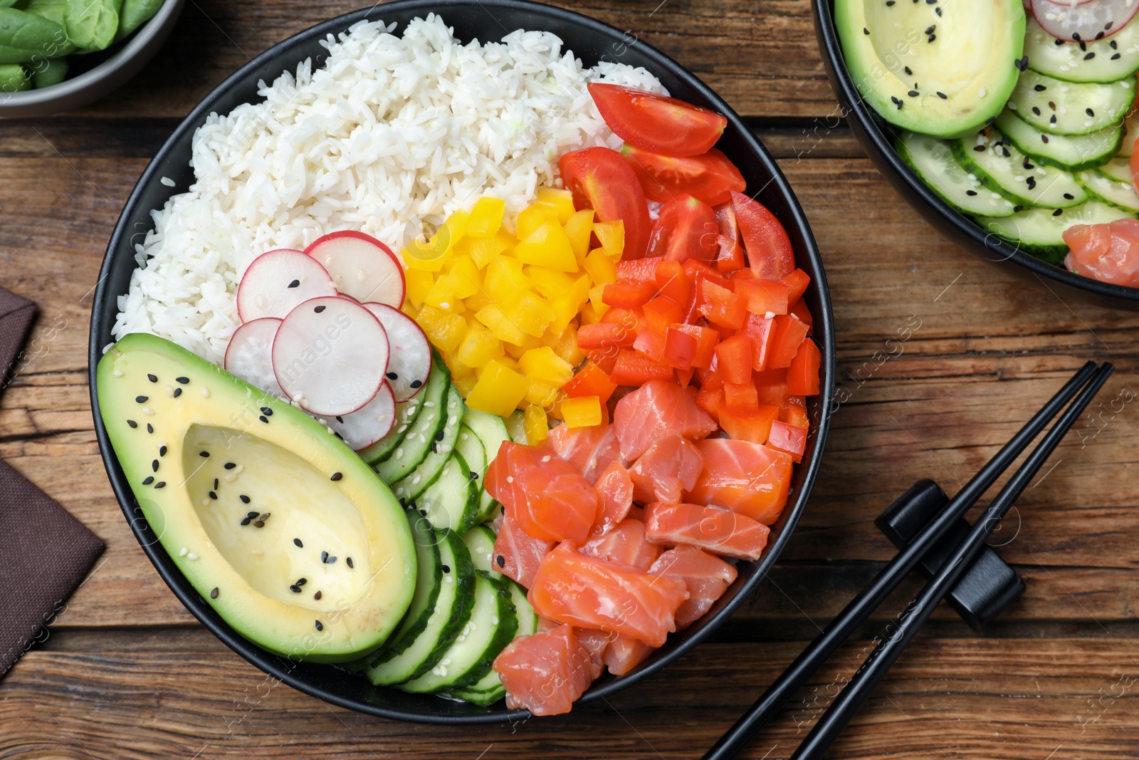 Photo of Delicious poke bowl with salmon and vegetables served on wooden table, flat lay