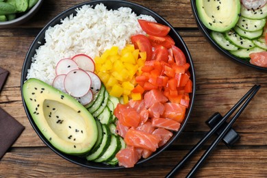 Delicious poke bowl with salmon and vegetables served on wooden table, flat lay