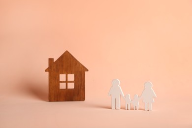 Photo of Figures of family and house on pink background. Space for text
