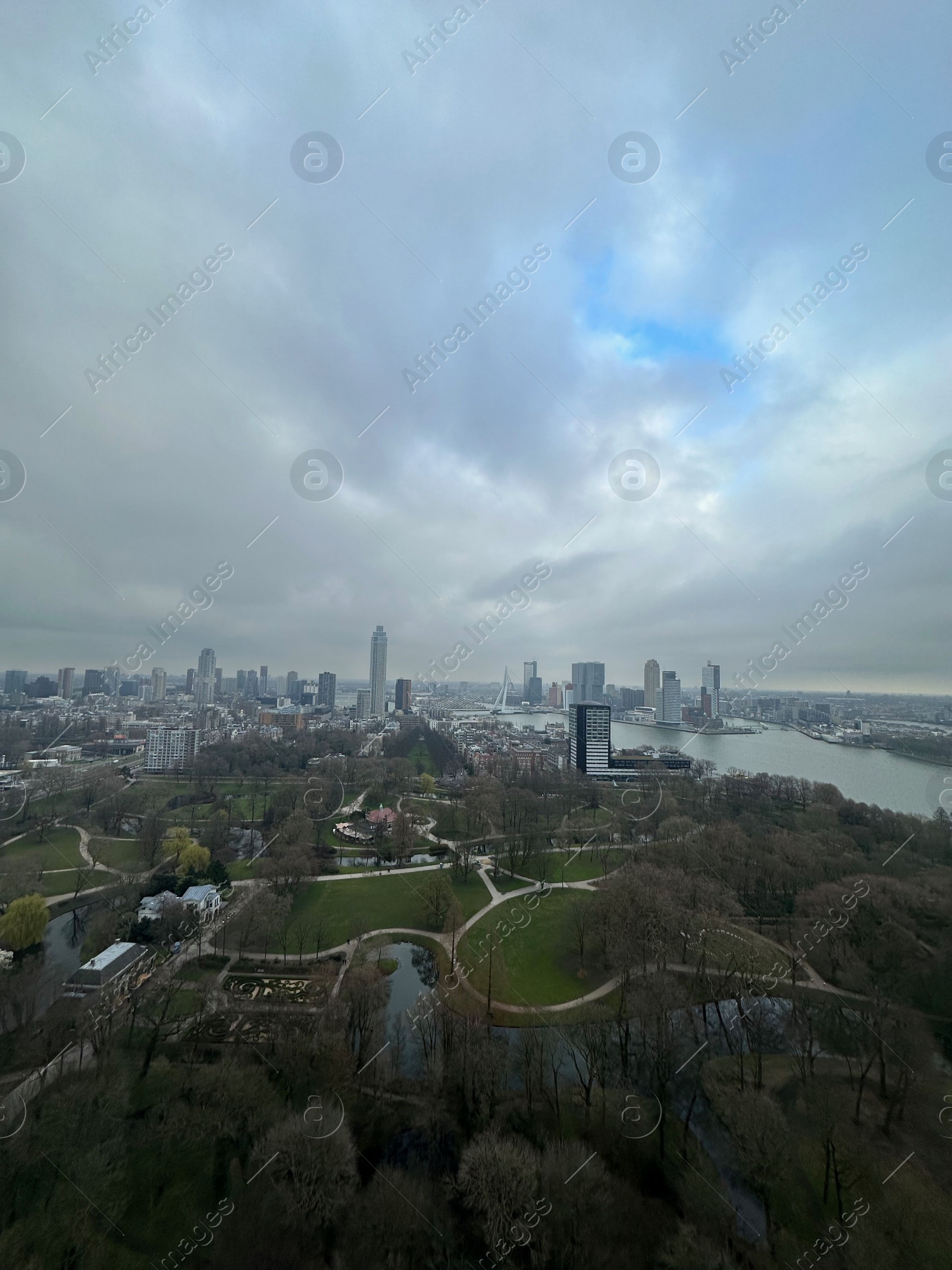 Photo of Picturesque view of city with modern buildings and park on cloudy day
