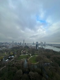 Picturesque view of city with modern buildings and park on cloudy day