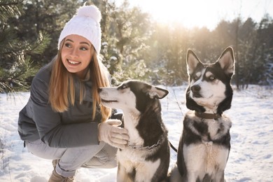 Photo of Young woman with dogs in forest on winter day