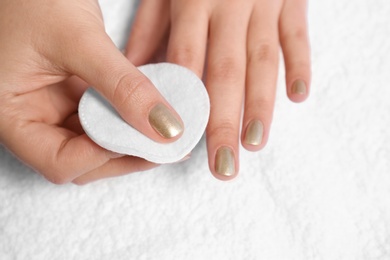 Photo of Woman removing nail polish on white fabric, closeup