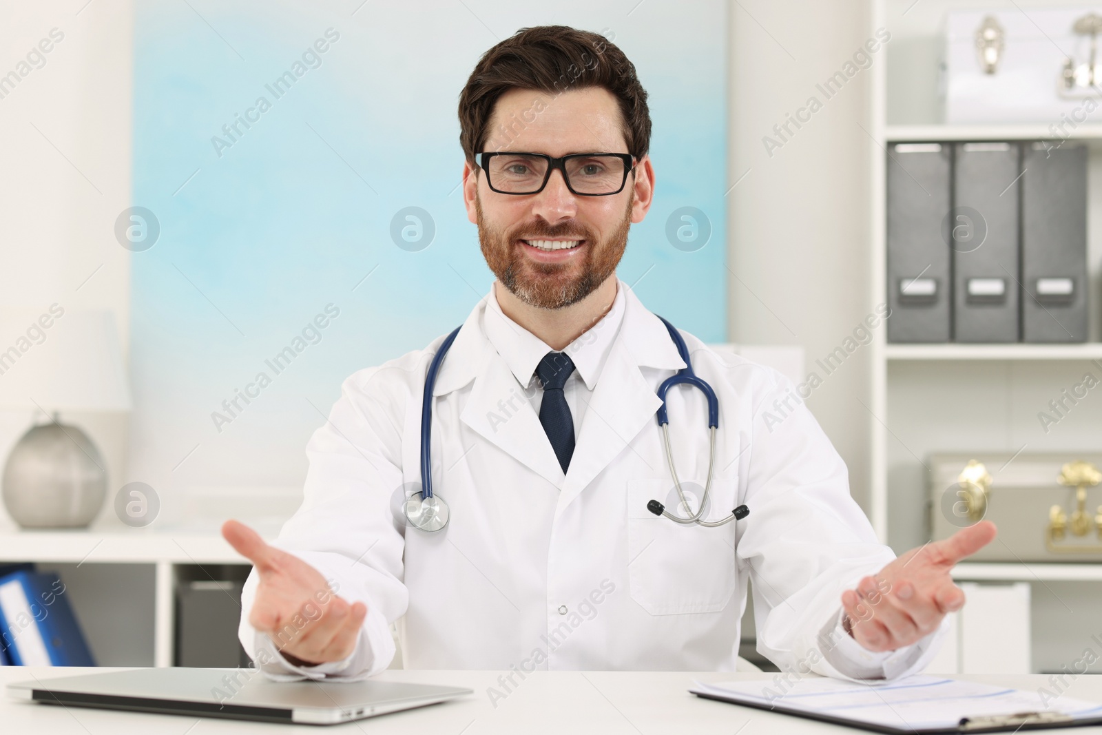 Photo of Medical consultant with glasses and stethoscope at table in clinic