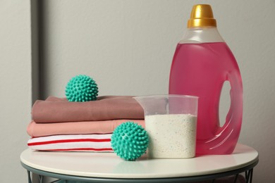 Turquoise dryer balls, detergents and stacked clean clothes on white table