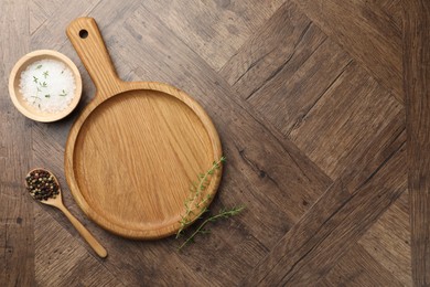 Photo of Cutting board and different spices on wooden table, flat lay. Space for text