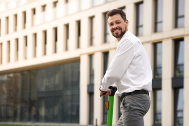 Businessman with modern kick scooter on city street, space for text