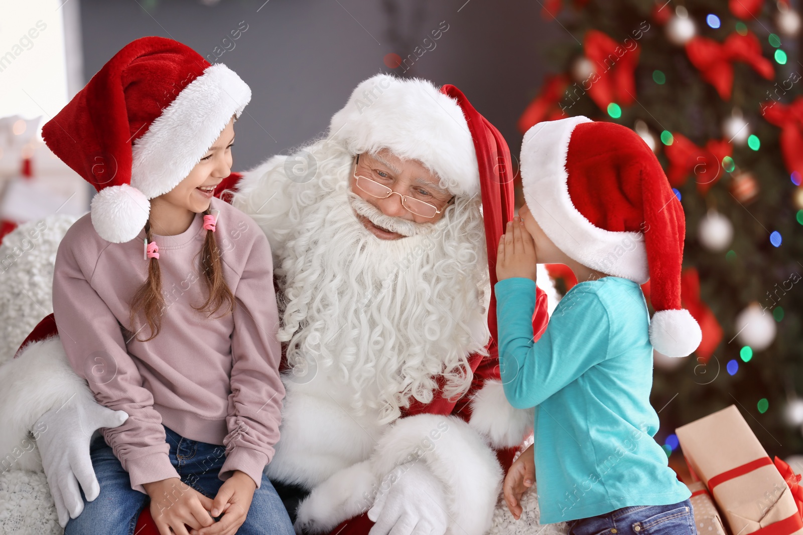 Photo of Little children sitting on authentic Santa Claus' knees indoors