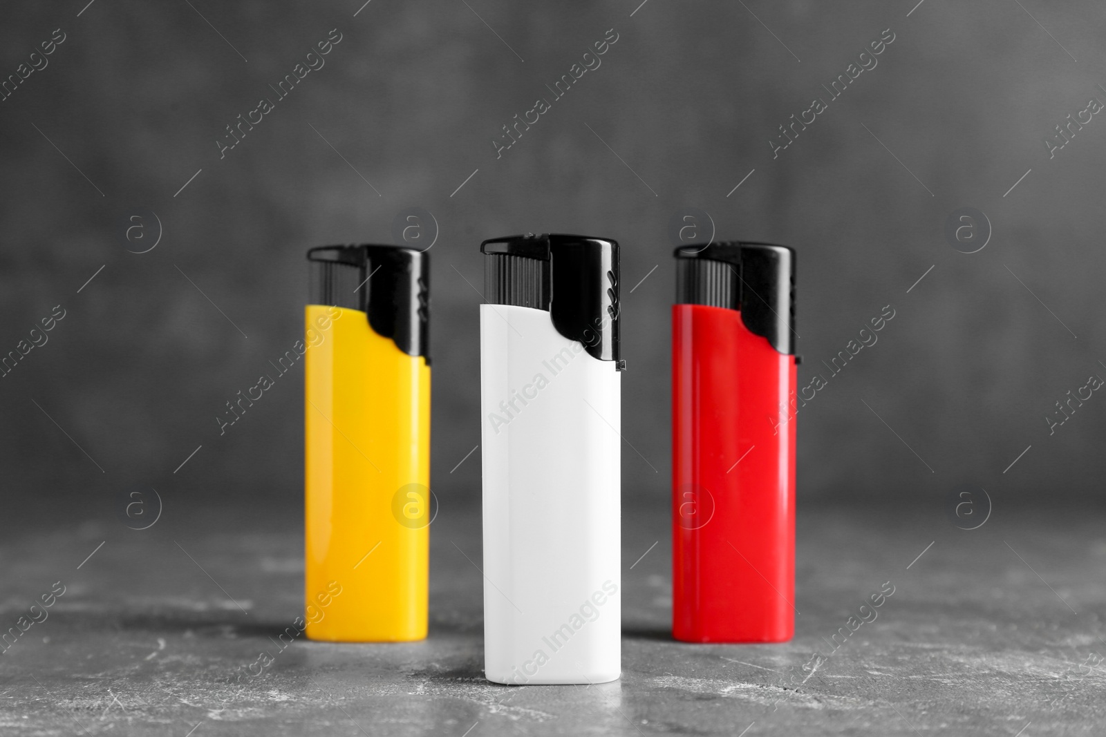 Photo of Stylish small pocket lighters on grey table