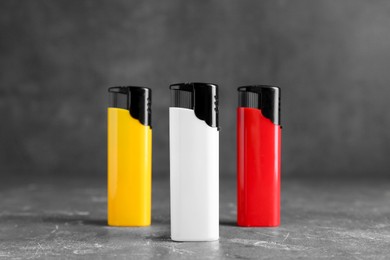 Photo of Stylish small pocket lighters on grey table