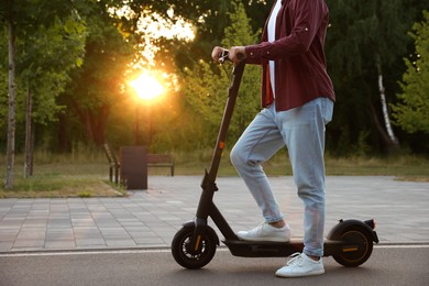 Photo of Man with modern electric kick scooter in park, closeup. Space for text