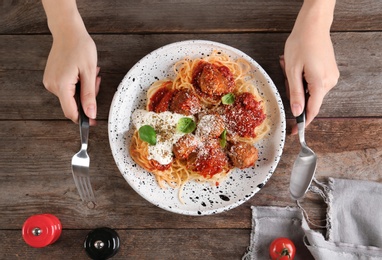 Woman having pasta with meatballs and tomato sauce at table, closeup