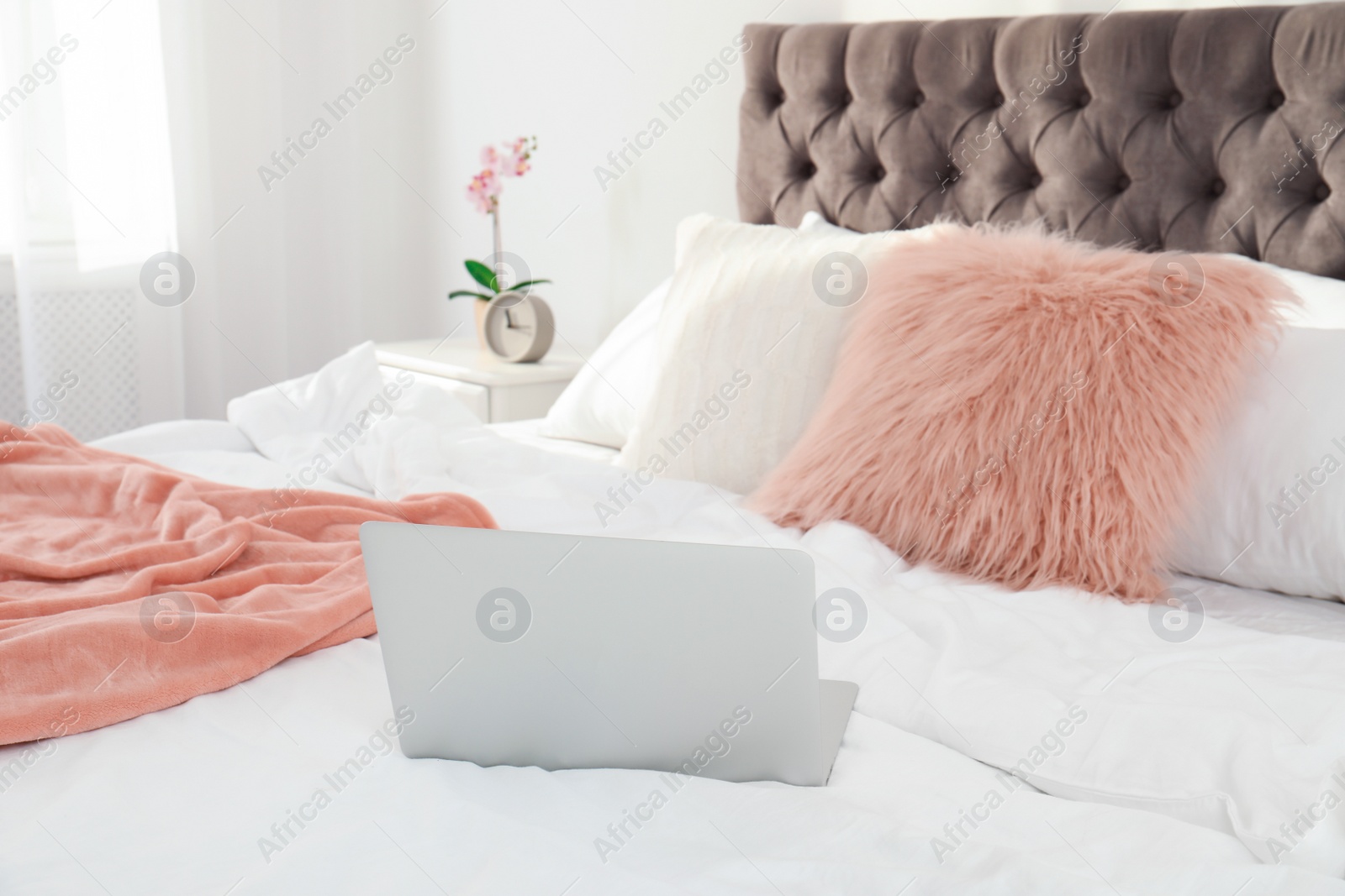 Photo of Laptop on bed in stylish room interior