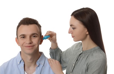 Photo of Woman dripping medication into man's ear on white background
