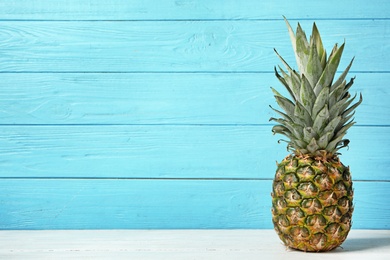 Photo of Fresh delicious pineapple on table against wooden background, space for text