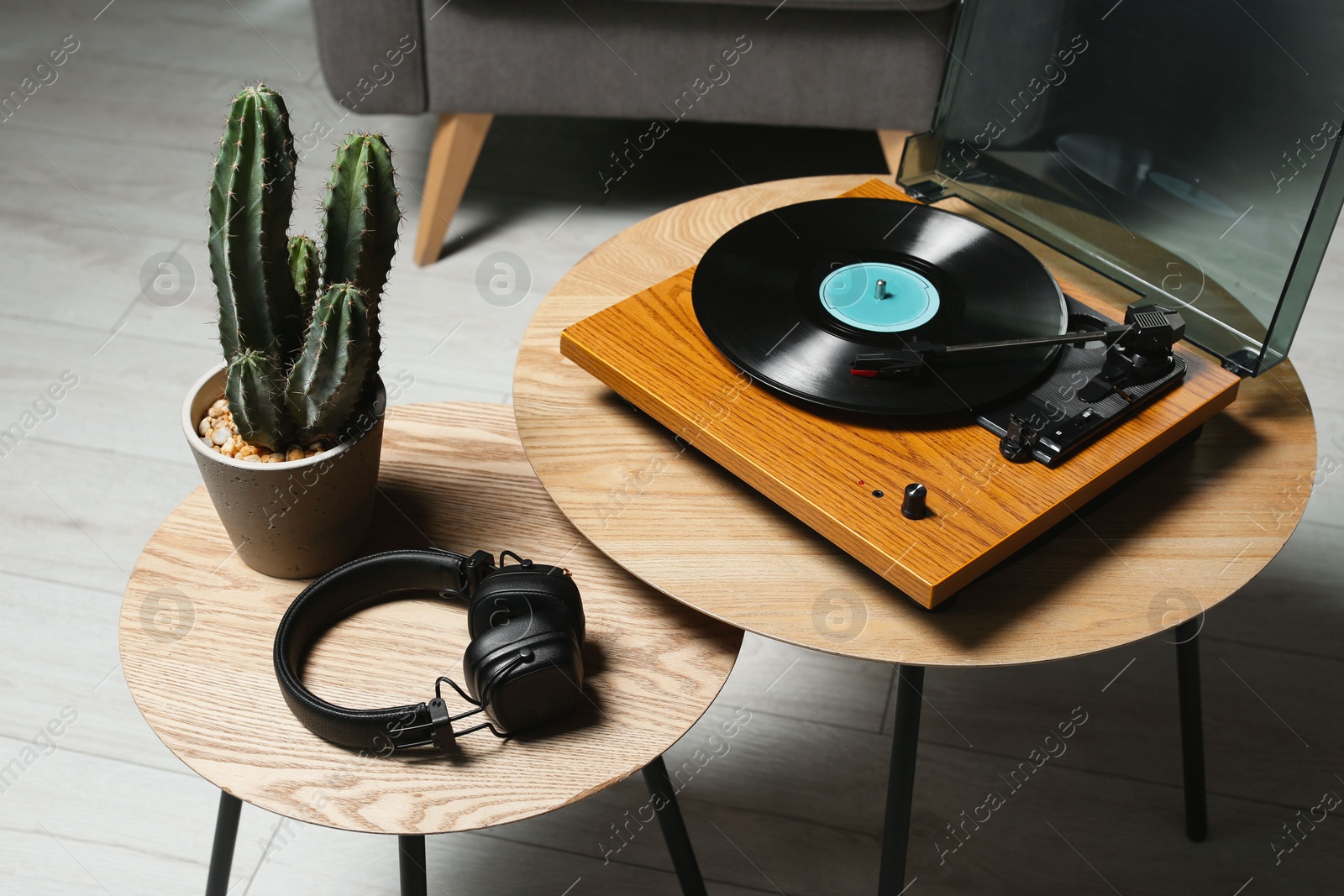 Photo of Stylish turntable with vinyl record, headphones and cactus on wooden table indoors